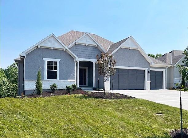 23217 W 124th Pl, Olathe, KS 66061 - view of front of property with a garage, a front yard, concrete driveway, and stucco siding
