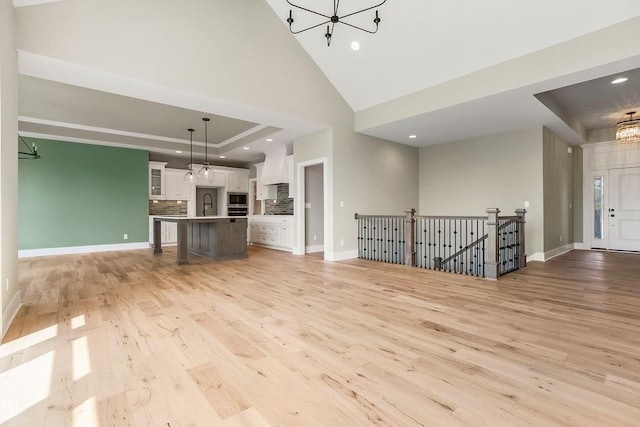 23217 W 124th Pl, Olathe, KS 66061 - unfurnished living room with a chandelier, light wood finished floors, recessed lighting, and a towering ceiling