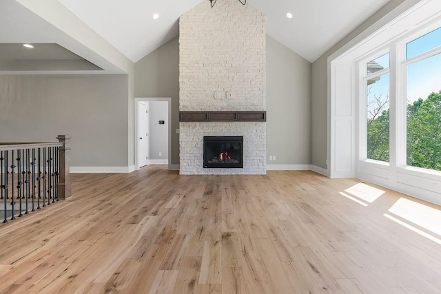 23217 W 124th Pl, Olathe, KS 66061 - unfurnished living room with healthy amount of natural light, high vaulted ceiling, light wood-type flooring, and a fireplace