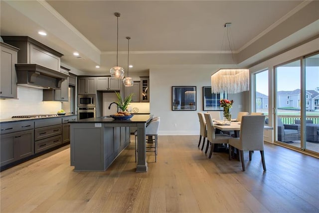 23217 W 124th Pl, Olathe, KS 66061 - kitchen featuring appliances with stainless steel finishes, gray cabinetry, a tray ceiling, crown molding, and light wood-style floors
