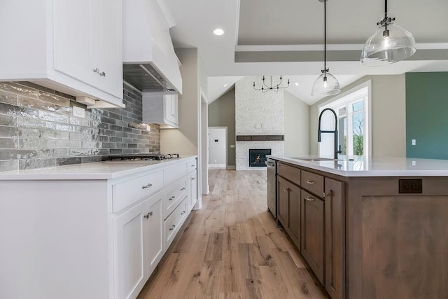 23217 W 124th Pl, Olathe, KS 66061 - kitchen featuring premium range hood, tasteful backsplash, lofted ceiling, white cabinets, and light countertops