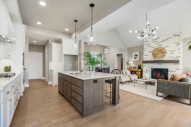 kitchen featuring light wood-type flooring, a sink, open floor plan, white cabinets, and appliances with stainless steel finishes