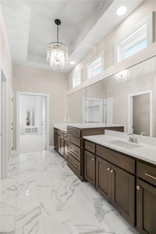 bathroom with a tray ceiling, a chandelier, marble finish floor, and vanity