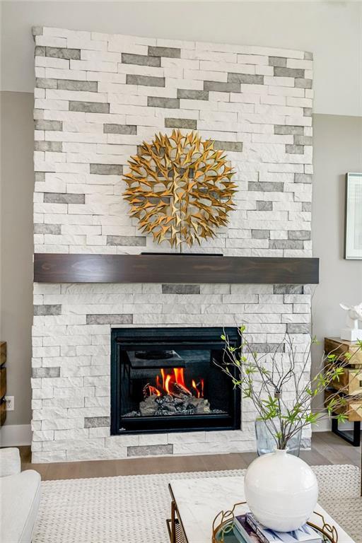 details with a stone fireplace and wood finished floors
