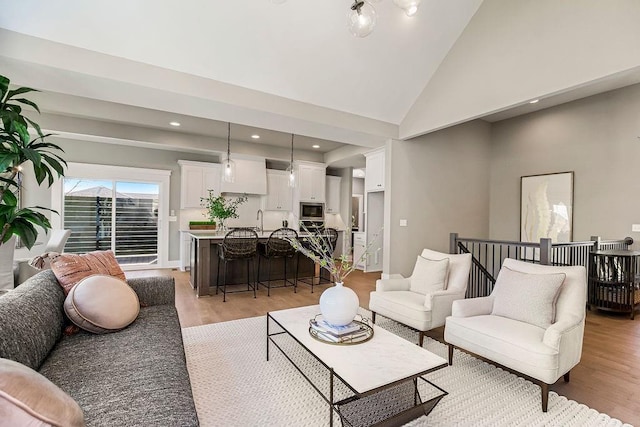 living area with high vaulted ceiling, light wood-type flooring, and recessed lighting