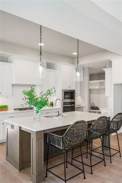 kitchen featuring white cabinets, a large island, gas stovetop, and a sink