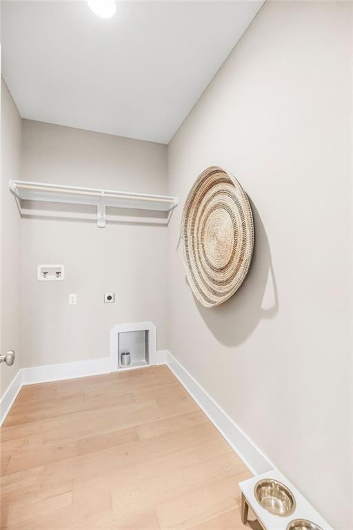 washroom with laundry area, hookup for an electric dryer, hookup for a washing machine, baseboards, and light wood-style floors