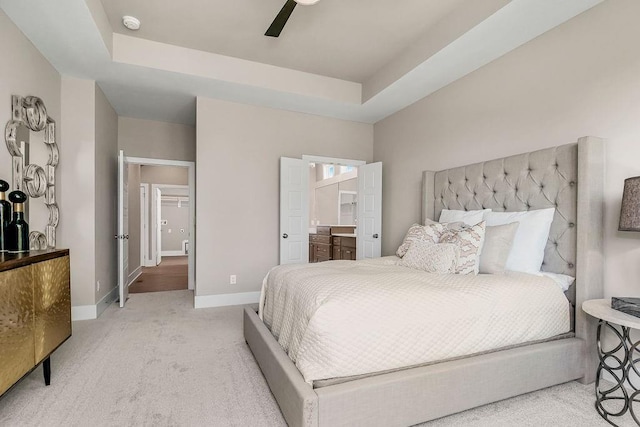bedroom featuring carpet flooring, ensuite bathroom, baseboards, and a raised ceiling