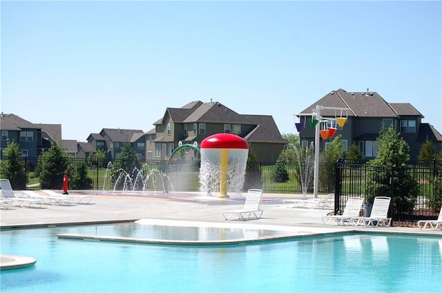 community pool with a patio, a residential view, and fence