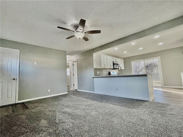 unfurnished living room featuring carpet flooring, a textured ceiling, and ceiling fan