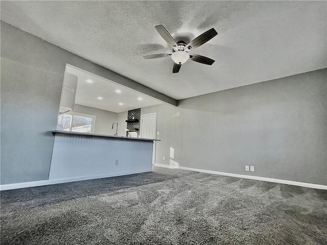 unfurnished living room with carpet floors, ceiling fan, a textured ceiling, and sink