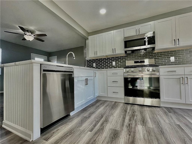 kitchen featuring light hardwood / wood-style floors, stainless steel appliances, ceiling fan, tasteful backsplash, and white cabinetry