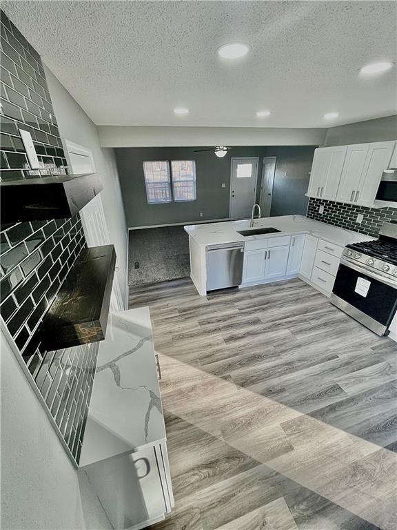 kitchen with light hardwood / wood-style flooring, white cabinetry, appliances with stainless steel finishes, backsplash, and sink