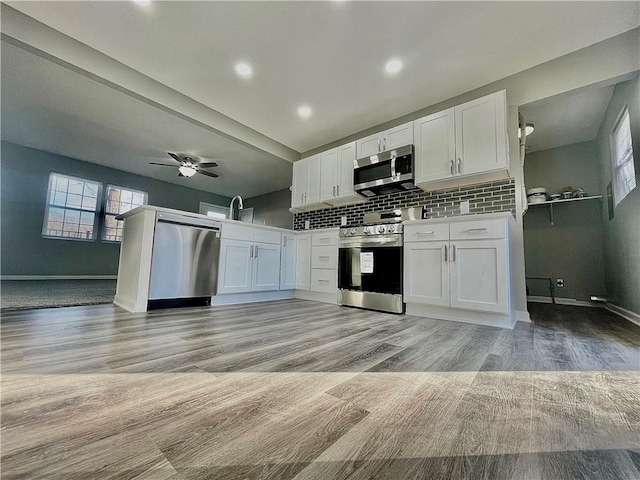 kitchen with stainless steel appliances, ceiling fan, white cabinets, and light hardwood / wood-style flooring