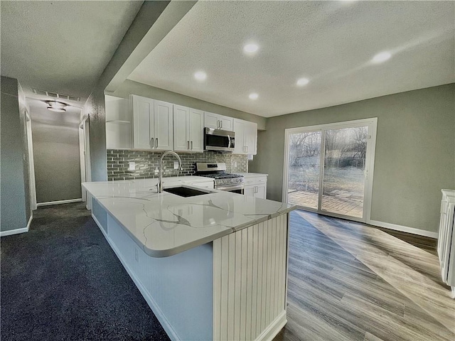 kitchen featuring sink, light stone counters, backsplash, stainless steel appliances, and white cabinetry