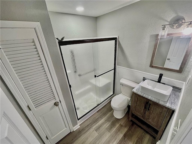 bathroom featuring toilet, hardwood / wood-style floors, a shower with shower door, and vanity