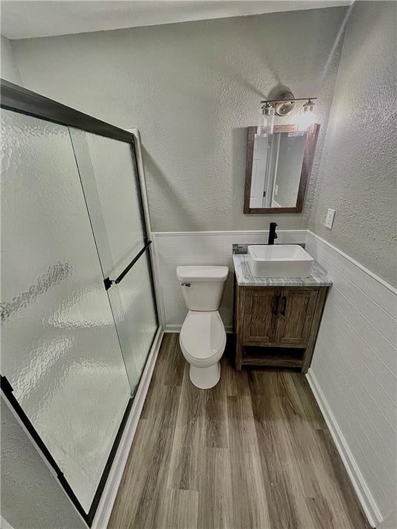 bathroom featuring toilet, hardwood / wood-style floors, vanity, and an enclosed shower