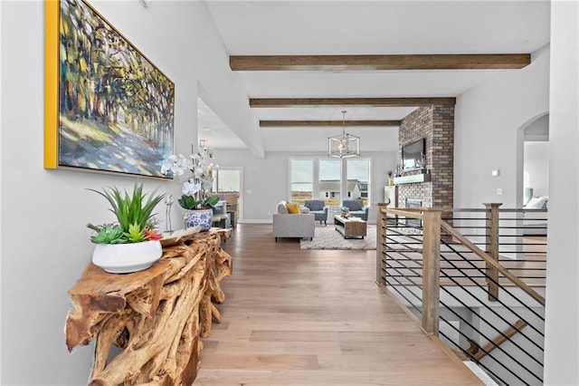 corridor featuring brick wall, light hardwood / wood-style flooring, and beam ceiling