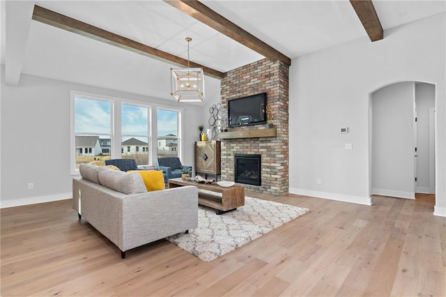 living room featuring beamed ceiling, a fireplace, hardwood / wood-style floors, and brick wall