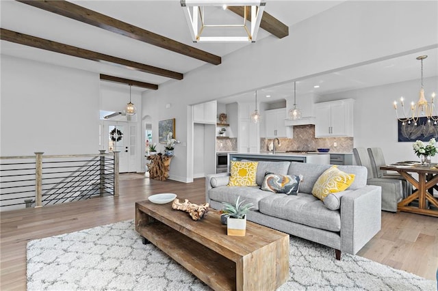 living room featuring beam ceiling, a chandelier, and light wood-type flooring