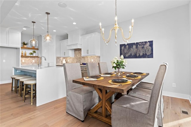 dining space with light hardwood / wood-style flooring, a notable chandelier, and sink