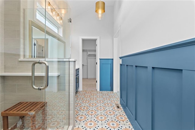 bathroom featuring a shower with shower door, a towering ceiling, tile floors, and vanity