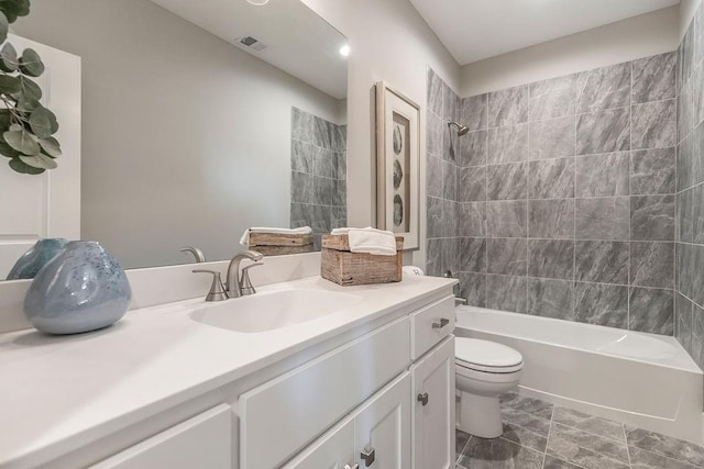 full bathroom with tiled shower / bath, toilet, large vanity, and tile floors