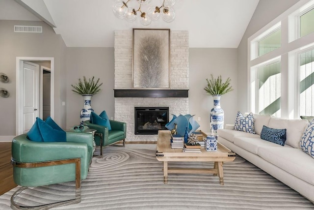 living room featuring a chandelier, a brick fireplace, brick wall, light wood-type flooring, and lofted ceiling