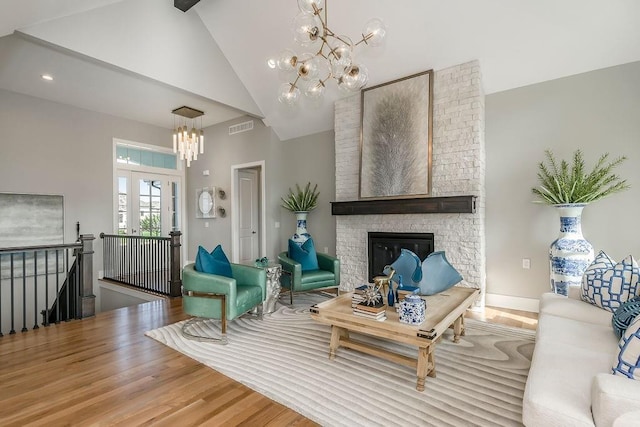 living room featuring a notable chandelier, a brick fireplace, brick wall, high vaulted ceiling, and hardwood / wood-style flooring