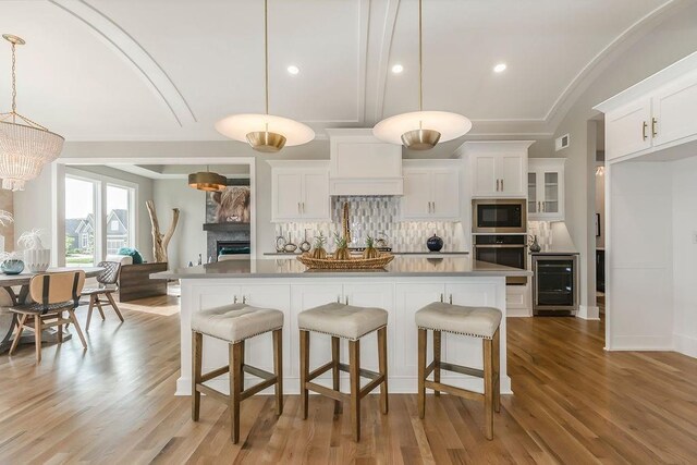 kitchen with white cabinetry, light hardwood / wood-style flooring, stainless steel appliances, tasteful backsplash, and pendant lighting