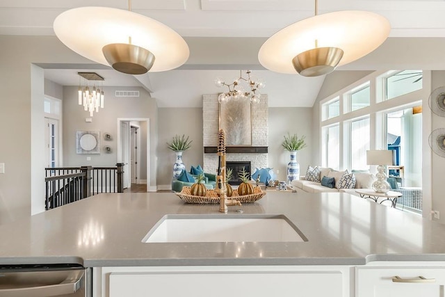 kitchen featuring decorative light fixtures, an inviting chandelier, white cabinets, dishwasher, and a fireplace