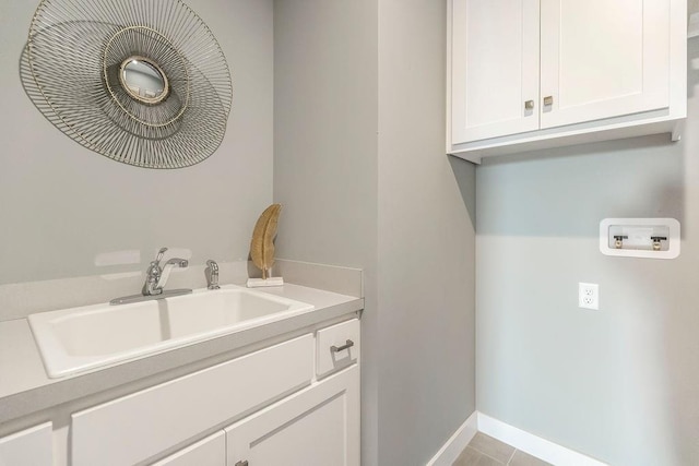 clothes washing area featuring light tile flooring, sink, cabinets, and hookup for a washing machine