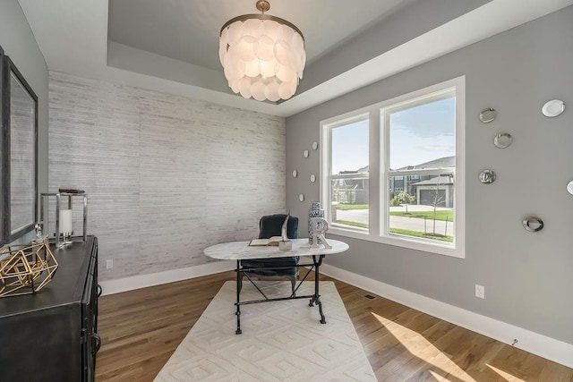 office space with a raised ceiling and light wood-type flooring