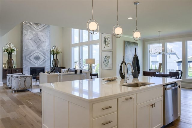 kitchen with white cabinetry, light wood-type flooring, pendant lighting, dishwasher, and a high end fireplace