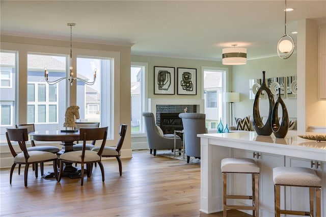 dining area featuring ornamental molding, a chandelier, a healthy amount of sunlight, and light hardwood / wood-style flooring