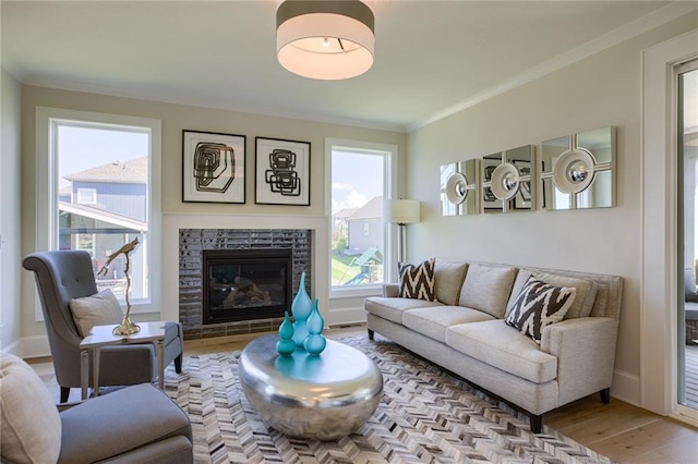 living room with a stone fireplace, light hardwood / wood-style flooring, and crown molding