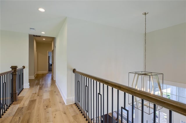 corridor with light hardwood / wood-style floors and a chandelier