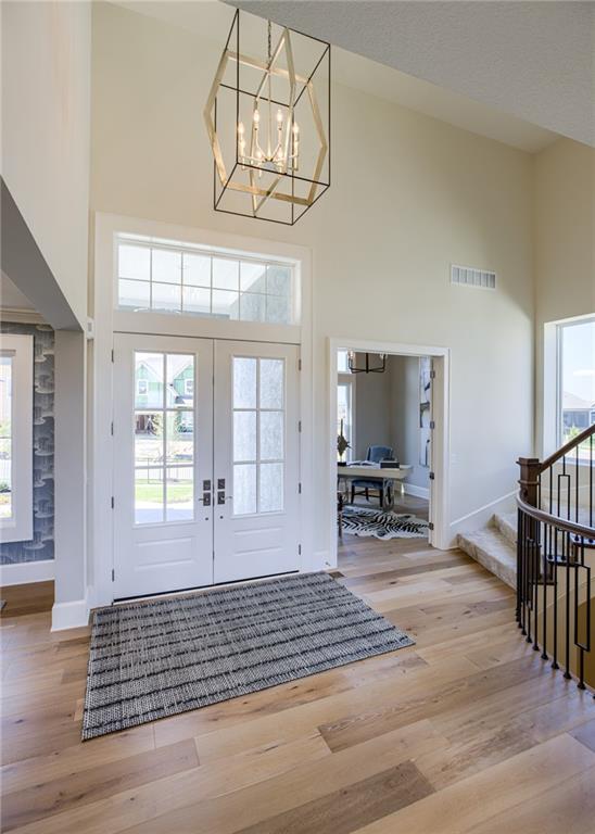 foyer with a chandelier, light wood-type flooring, high vaulted ceiling, and french doors