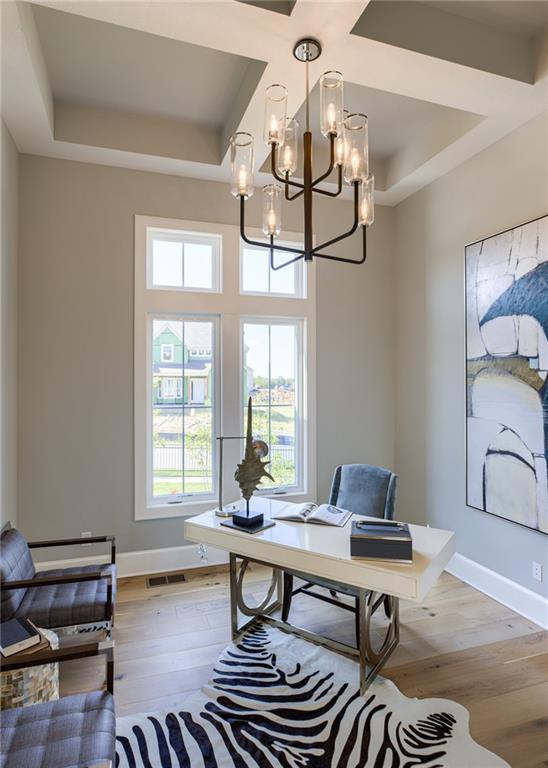 home office featuring a tray ceiling, a chandelier, and light hardwood / wood-style floors