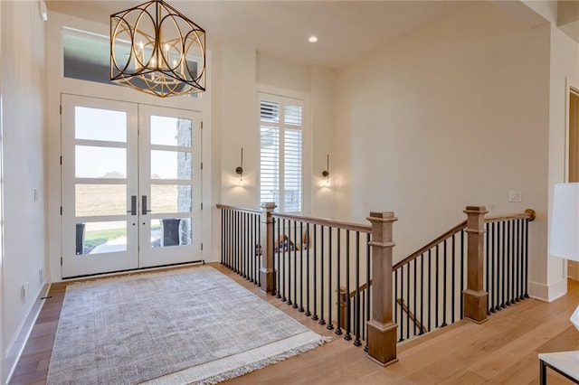 foyer entrance with an inviting chandelier, light wood-type flooring, french doors, and a healthy amount of sunlight