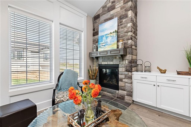 living room featuring a fireplace, lofted ceiling, a healthy amount of sunlight, and light wood-type flooring