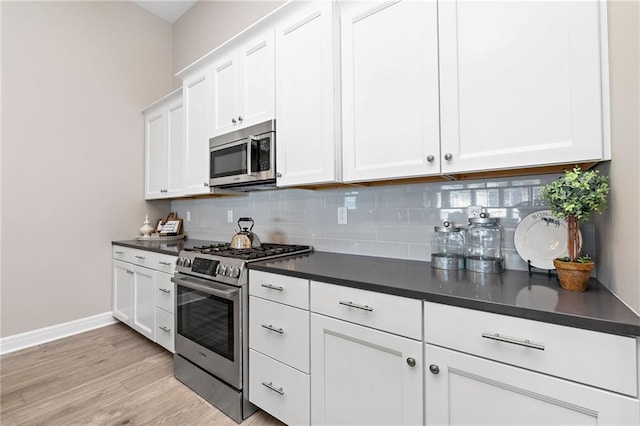 kitchen with light wood-type flooring, tasteful backsplash, appliances with stainless steel finishes, and white cabinetry