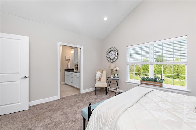 carpeted bedroom with ensuite bathroom and high vaulted ceiling