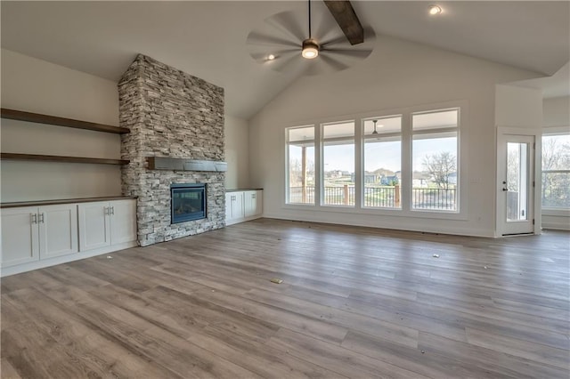 unfurnished living room with light hardwood / wood-style floors, ceiling fan, a healthy amount of sunlight, and a stone fireplace