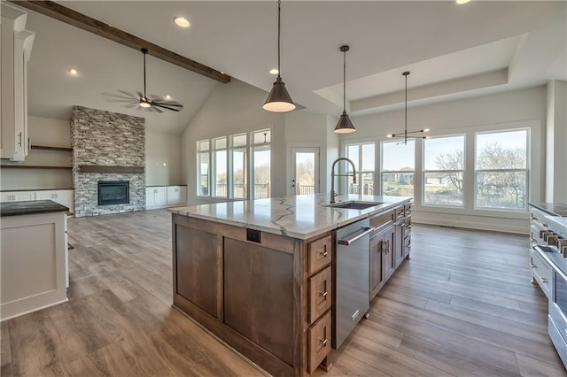 kitchen with hanging light fixtures, white cabinetry, a fireplace, light hardwood / wood-style flooring, and sink