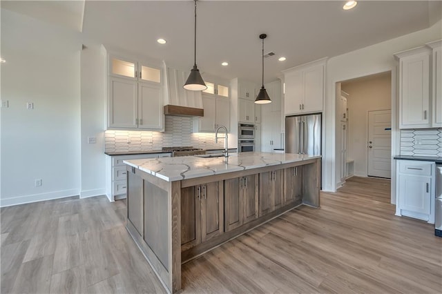 kitchen with a center island with sink, stainless steel appliances, and white cabinets