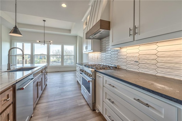 kitchen featuring dark stone counters, white cabinets, stainless steel appliances, and wall chimney range hood