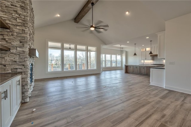 unfurnished living room featuring light hardwood / wood-style flooring, ceiling fan, plenty of natural light, and a fireplace