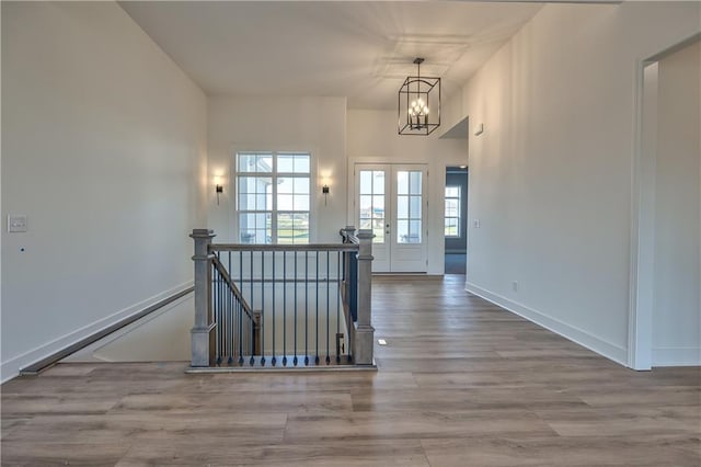 interior space featuring a notable chandelier, light hardwood / wood-style floors, french doors, and plenty of natural light