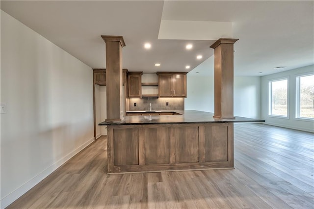 kitchen featuring backsplash, decorative columns, sink, and hardwood / wood-style flooring